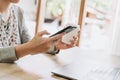 Woman using phone and holding coffee working on wooden table Royalty Free Stock Photo