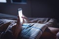 Woman using phone late at night in bed. Person looking at text messages with cell in dark home. Hipster online dating or texting.