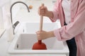 Woman using plunger to unclog sink drain in kitchen, closeup Royalty Free Stock Photo