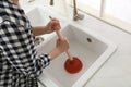 Woman using plunger to unclog sink drain in kitchen, closeup Royalty Free Stock Photo