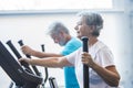 Woman using a precor at the gym - active senior with his man at the background - couple of pensioners doing exercises together Royalty Free Stock Photo