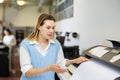 Woman using printer while working in print shop Royalty Free Stock Photo