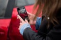 Woman using a smart phone to take a photo of the damage to her car caused by a car crash. Royalty Free Stock Photo