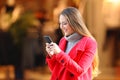 Woman using a smart phone in winter in a commercial centre