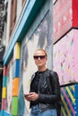 Woman using smartphone against colorful graffiti wall in New York city, USA.