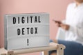 Woman using smartphone against pink background, focus on lightbox with phrase DIGITAL DETOX