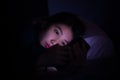 Woman using smartphone on bed at night. Young Asian woman holding mobile phone on bed in dark room. Mobile addict concept Royalty Free Stock Photo