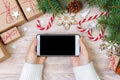Woman using smartphone with blank screen, festive trumpery frame. Christmas gift search, online shopping, seasonal discounts and s