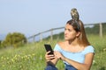 Woman using smartphone disgusted with an owlet on head Royalty Free Stock Photo