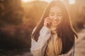 Woman using smartphone in fall. Autumn girl having smart phone conversation in sun flare foliage. Portrait of Caucasian Royalty Free Stock Photo