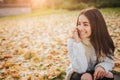 Woman using smartphone in fall. Autumn girl having smart phone conversation in sun flare foliage. Portrait of Caucasian Royalty Free Stock Photo