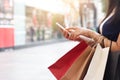 Woman using smartphone while holding shopping bags