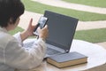 Woman using smartphone and laptop computer on octagon marble table in front yard area