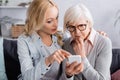 Woman using smartphone near pensive mother