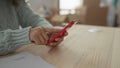 Woman using smartphone in new apartment surrounded by unpacked boxes while checking documents on wooden table, creating cozy home Royalty Free Stock Photo