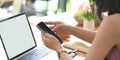 A woman is using a smartphone while sitting in front of a white blank screen computer laptop Royalty Free Stock Photo