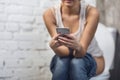 Woman Using Smartphone Sitting On Toilet In Restroom, Cropped