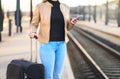 Woman using smartphone in train station while waiting. Royalty Free Stock Photo