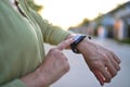 Woman using smartwatch touching button and touchscreen Standing outside.