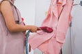 Woman using steaming iron to ironing fashion shirt in laundry room. Girl doing stream vapor iron for press clothes in hand. Royalty Free Stock Photo