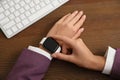 Woman using stylish smart watch at table, closeup