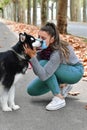 Woman using a surgical mask crouching down and holding a beautiful dog's head in the street