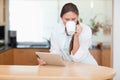 Woman using a tablet computer while drinking coffee Royalty Free Stock Photo