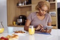 Woman using tablet computer while eating breakfast at home Royalty Free Stock Photo