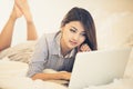 Woman using a tablet computer while lying on her bed Royalty Free Stock Photo