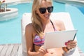 Woman using tablet computer by the pool