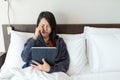 Woman using tablet and feeling eye pain and lying on bed Royalty Free Stock Photo