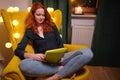 Woman using a tablet on line at home sitting on a yellow in the living room at home . Covid isolation