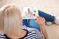 Woman using tablet for online consultation with doctor via video chat at home