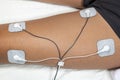 Woman using TENS and EMS machine at home on the muscle of one of her leg