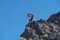 Woman Using Trekking Poles To Descend Steep Rock