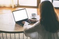 A woman using and typing on laptop with blank white desktop screen on the table while sitting on the floor in the Royalty Free Stock Photo