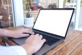 A woman using and typing on laptop with blank white screen and coffee cup on table in modern cafe Royalty Free Stock Photo