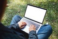 A woman using and typing on laptop with blank white screen , sitting in the outdoors Royalty Free Stock Photo