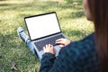 A woman using and typing on laptop with blank white screen , sitting in the outdoors with nature background Royalty Free Stock Photo