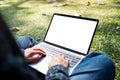 A woman using and typing on laptop with blank white screen , sitting in the outdoors with nature background Royalty Free Stock Photo