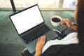 A woman using and typing on laptop computer with blank white desktop screen while drinking coffee in office Royalty Free Stock Photo