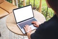 A woman using and typing on laptop computer keyboard with blank white desktop screen on wooden table Royalty Free Stock Photo