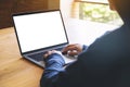 A woman using and typing on laptop computer keyboard with blank white desktop screen on wooden table Royalty Free Stock Photo