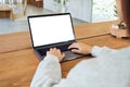 A woman using and typing on laptop computer keyboard with blank white desktop screen on wooden table Royalty Free Stock Photo