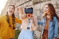 Woman using VR headset glasses 360, VR experience outdoor. Visual reality concept. Excited three girls experiencing virtual
