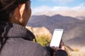 A woman using white mobile phone with blank screen while standing in front of mountain and blue sky Royalty Free Stock Photo