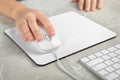 Woman using wired computer mouse on pad at grey marble table, closeup Royalty Free Stock Photo