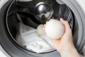 Woman using wool dryer balls for more soft clothes while tumble drying in washing machine concept