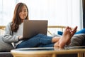 A woman using and working on laptop computer while lying on a sofa at home Royalty Free Stock Photo
