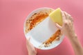 Woman using yellow cleaning sponge to clean up and washing food stains and dirt on white dish after eating meal  on pink Royalty Free Stock Photo